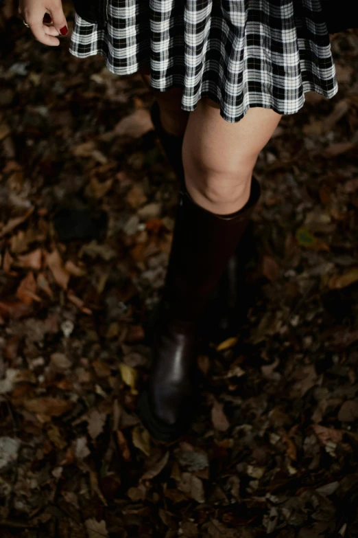 a woman in boots holding a black and white striped purse