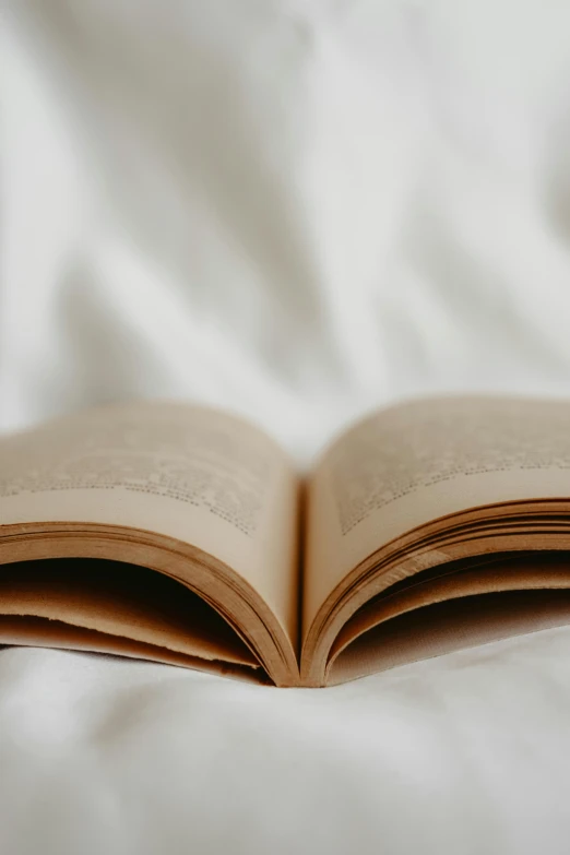 an open book lying on top of a bed