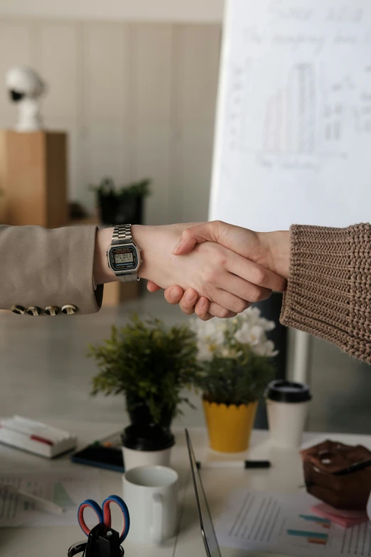 two people hold their hands while sitting at a desk