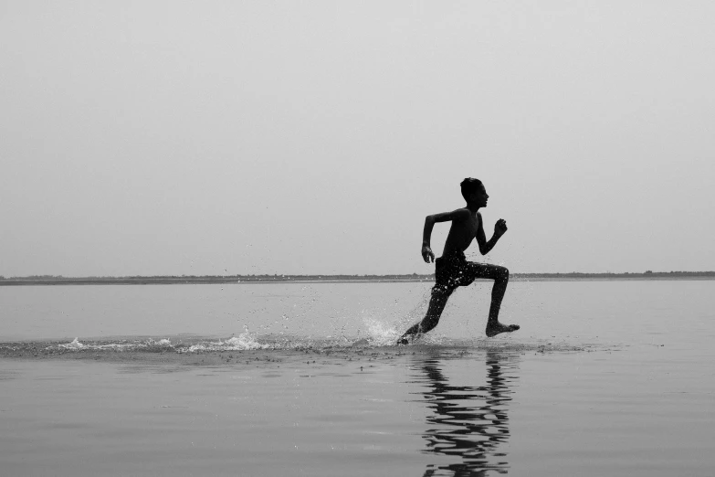 a man running through the water with no shoes