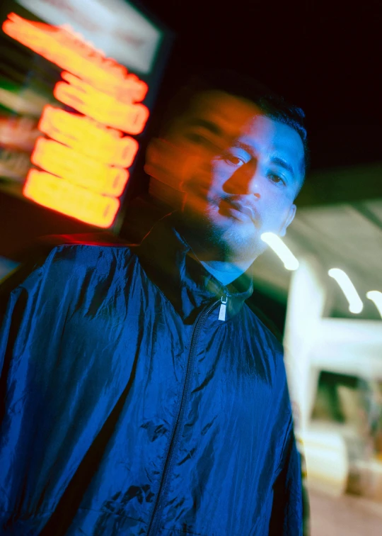 a man standing under an umbrella with a neon light behind him