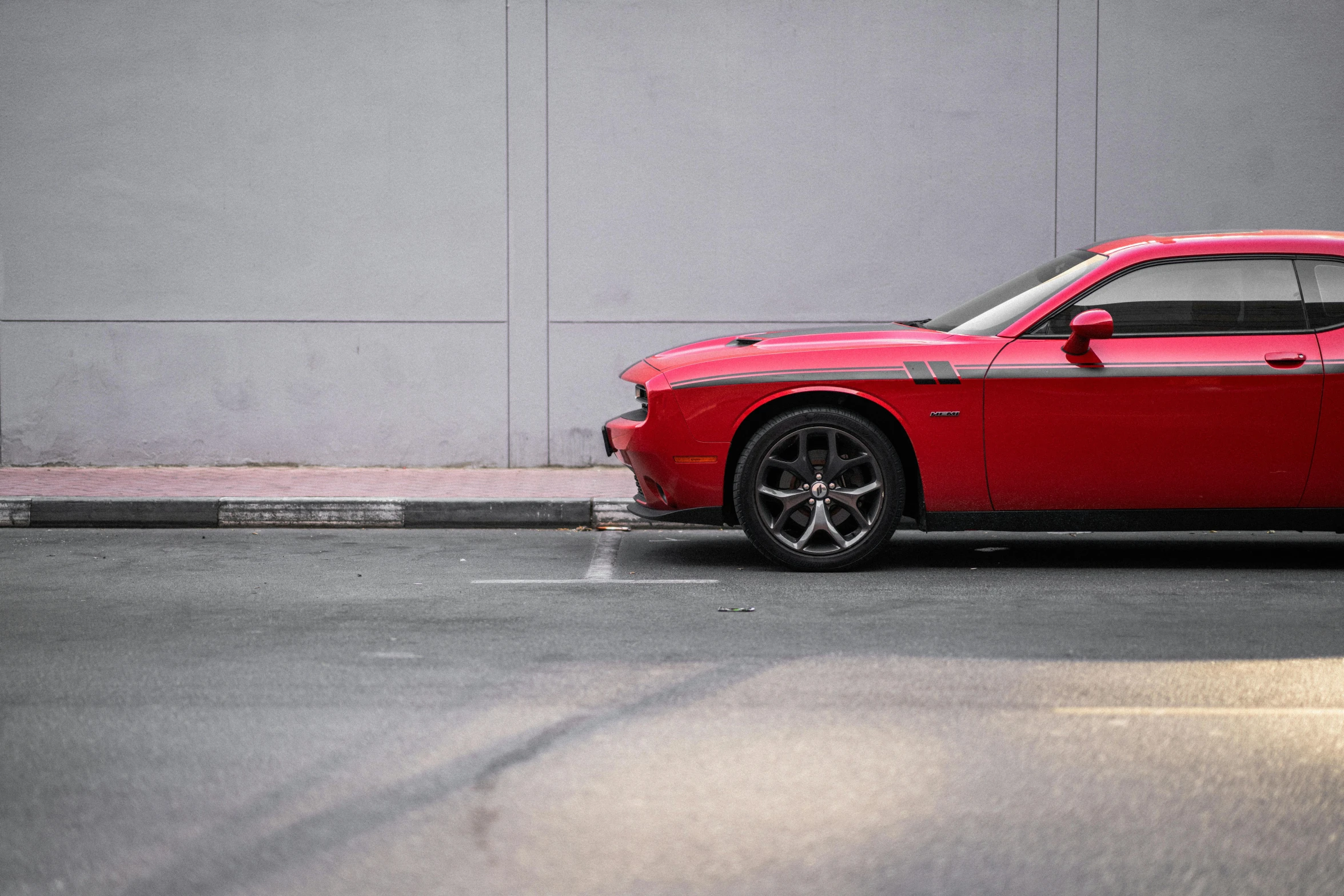 a red sports car is parked next to a wall