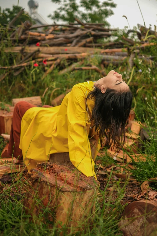 a young woman laying on top of a stump covered forest