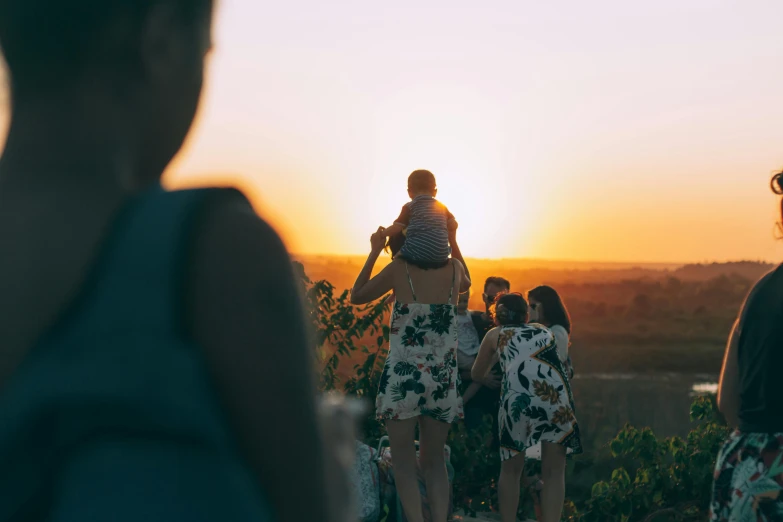 a group of people standing on top of a hill at sunset