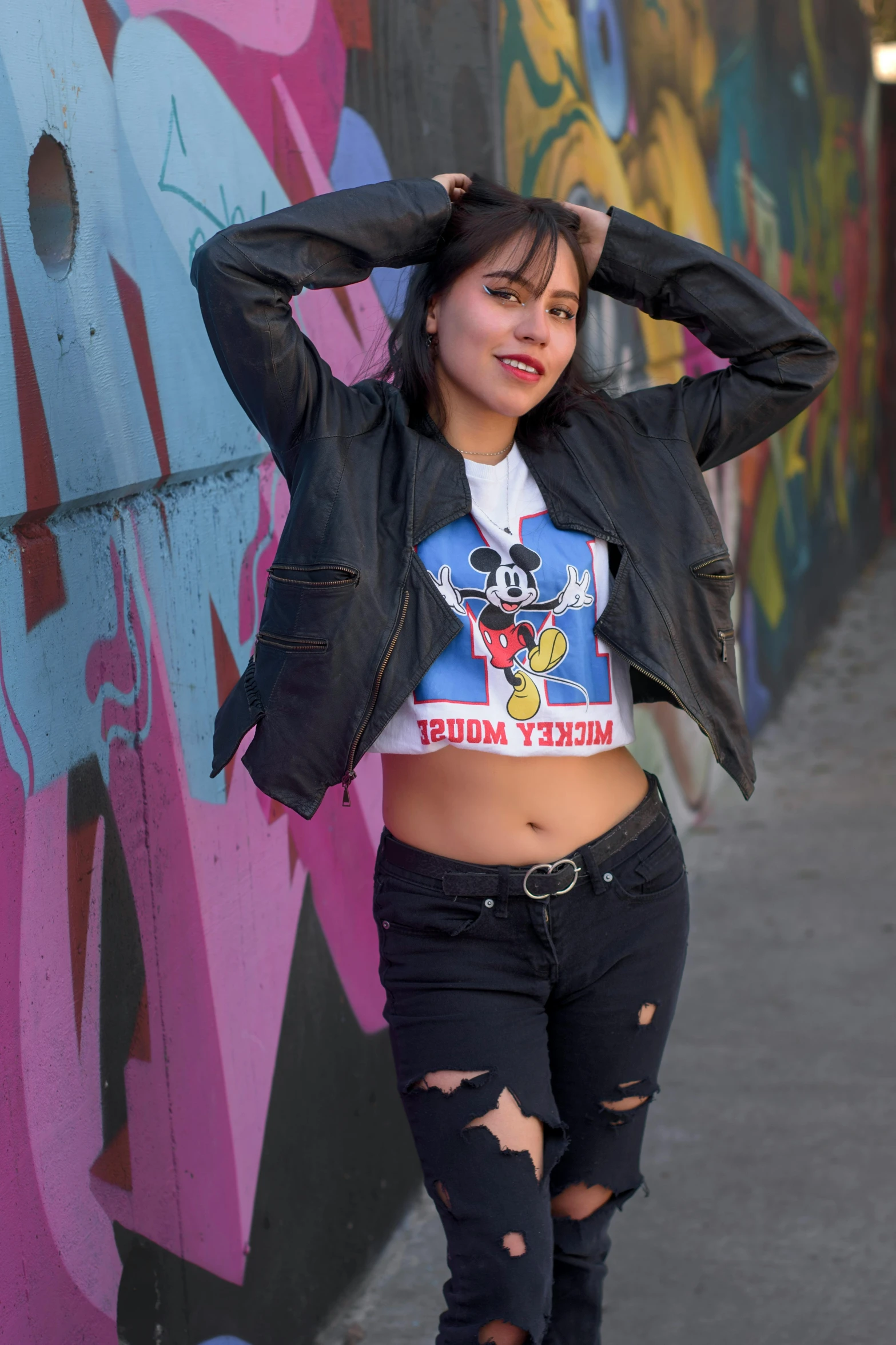 young woman posing for a picture in front of colorful graffiti