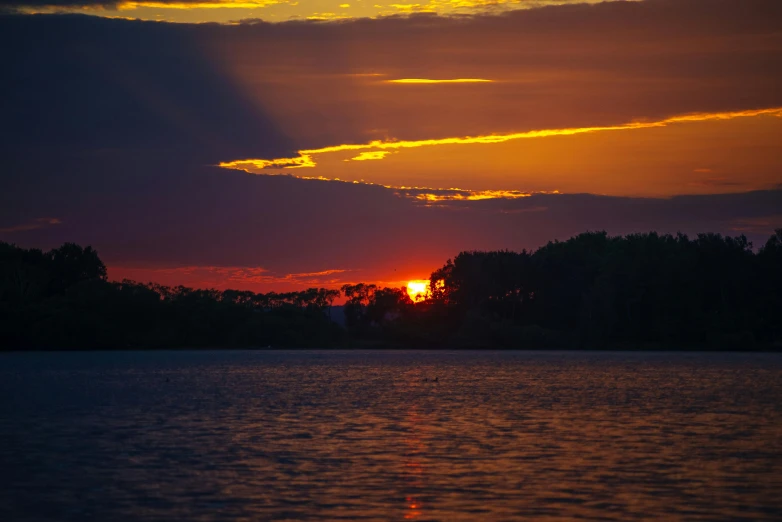 the sun setting over a lake and the clouds