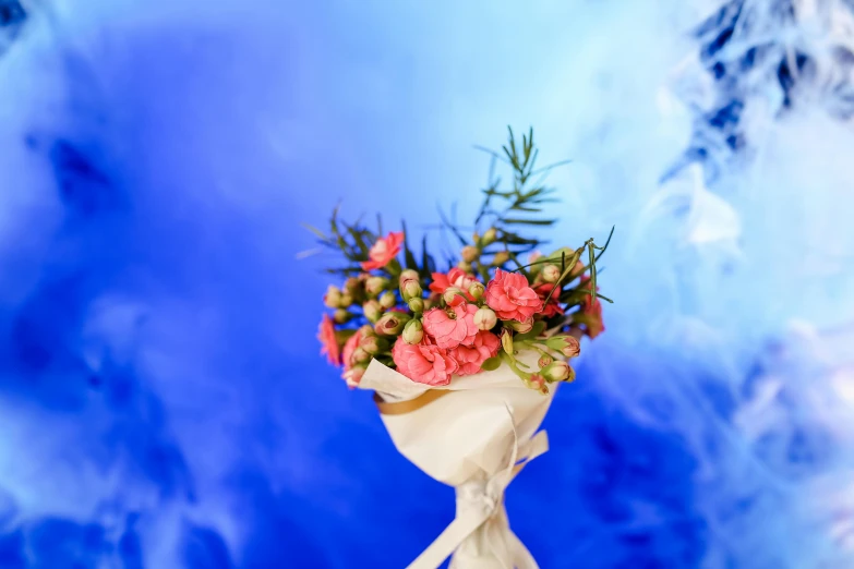 a floral arrangement with white ribbon and blue skies