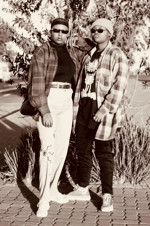 black and white pograph of two men leaning against tree