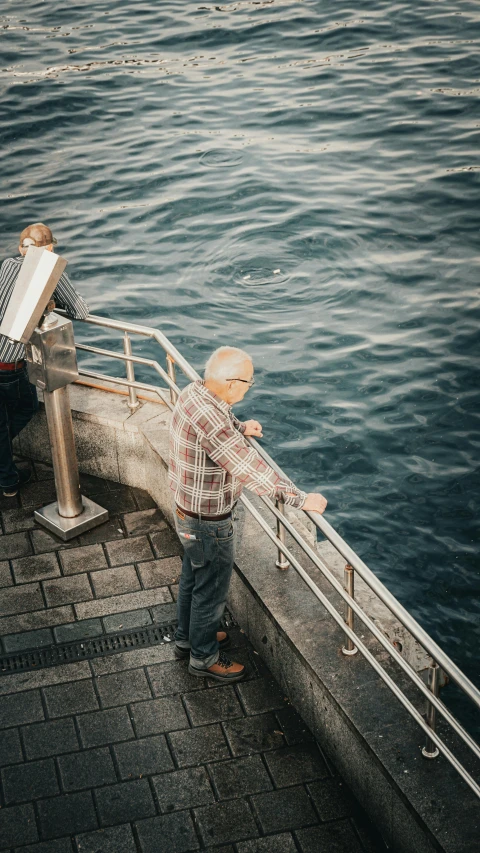 there is a man standing at the railing looking out over water