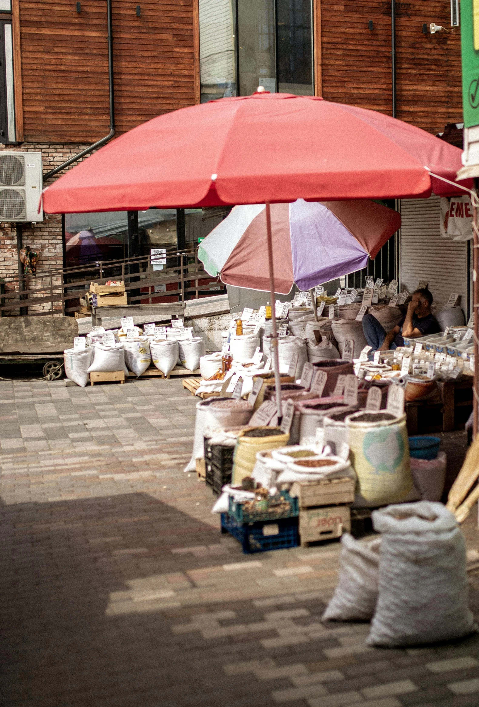 a red umbrella is placed over items for sale on the street