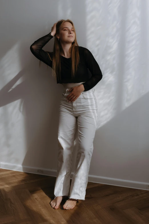 a woman standing next to a white wall wearing black