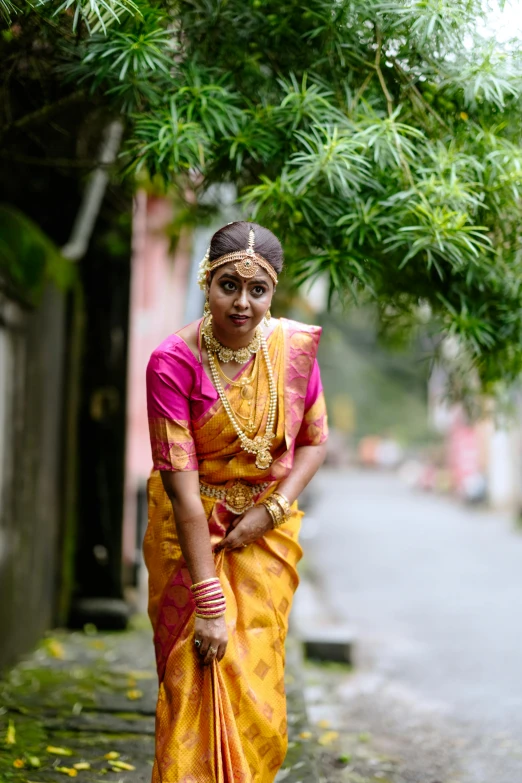 the woman is wearing a pink and yellow traditional sari