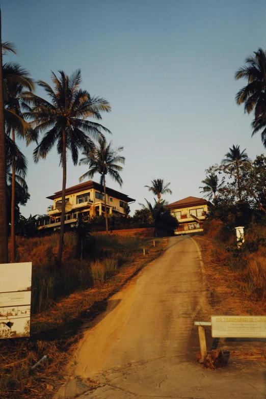 a dirt road with a bench in the foreground and some houses on both sides