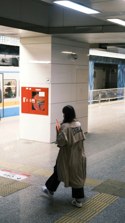 person in trench coat carrying suitcase down the street