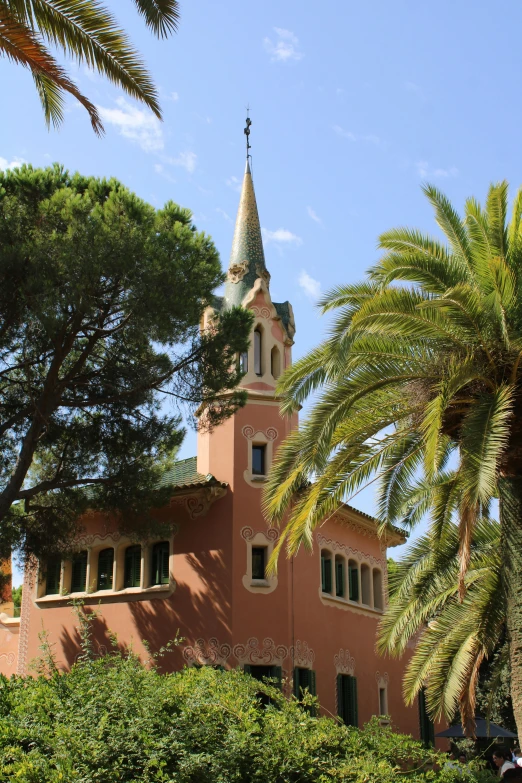 a church building with a tower and spire next to palm trees