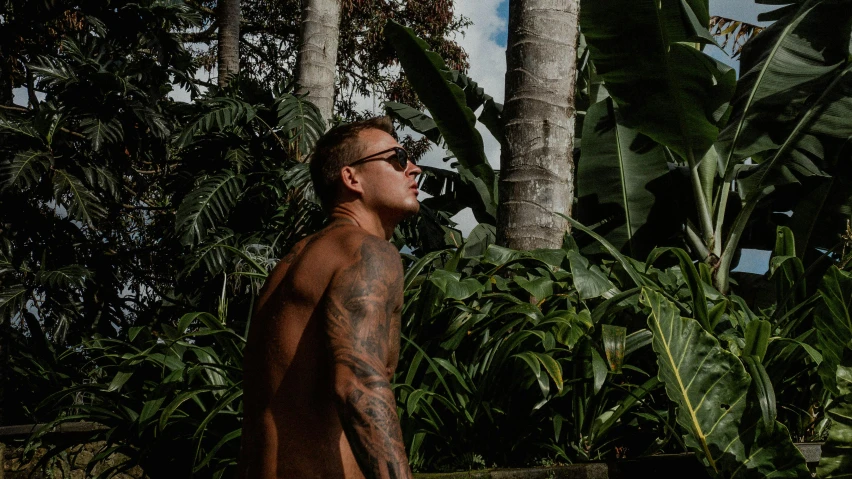 there is a man with a lot of tattoos standing in the forest