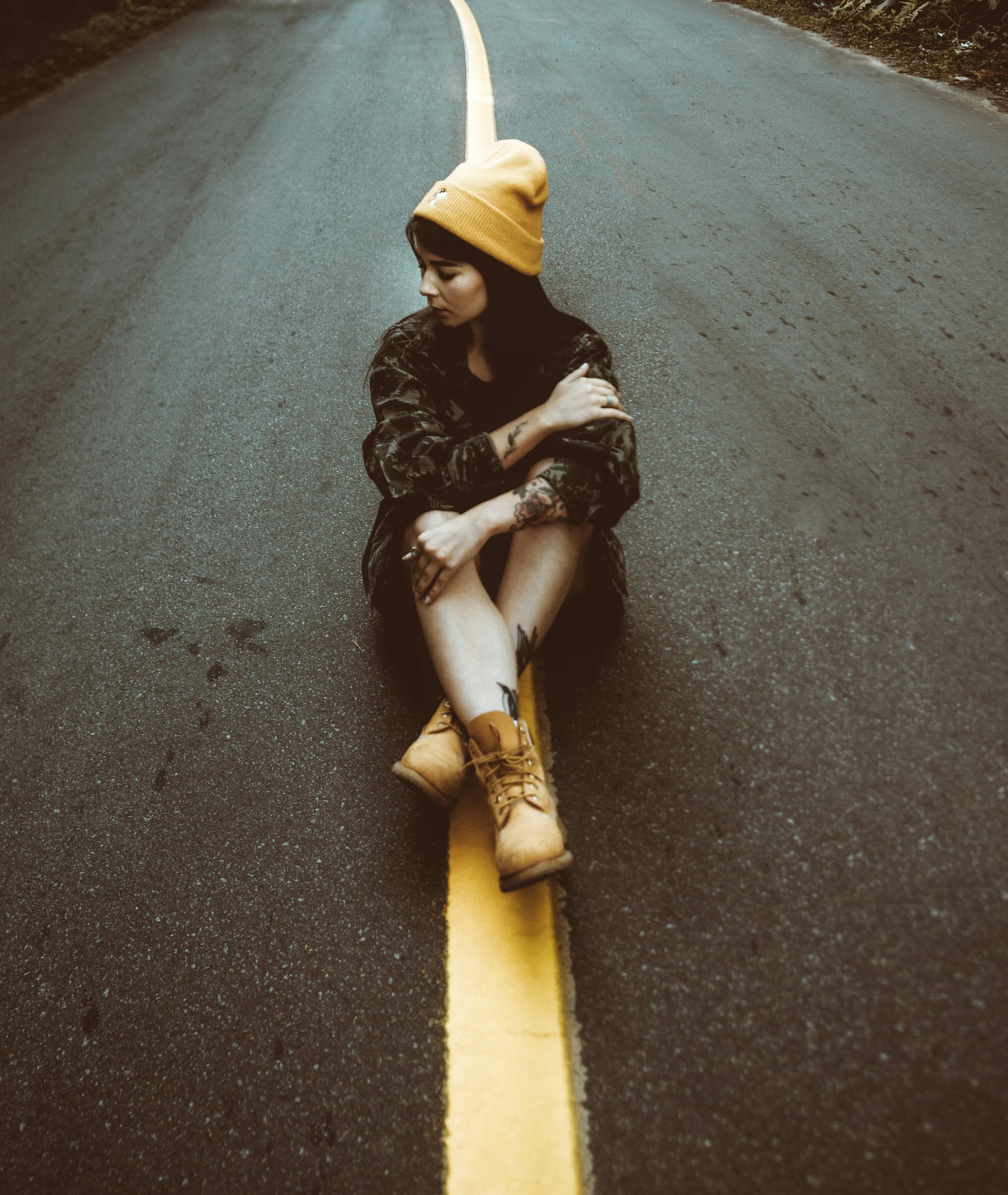 a man sits on the road wearing boots and a yellow hat