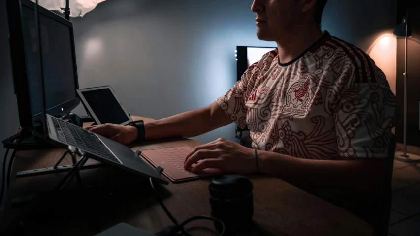 a man sitting at his desk using a laptop