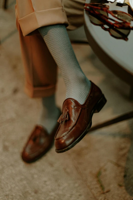 a man's shoes with a rope hanging off of the side of his shoe