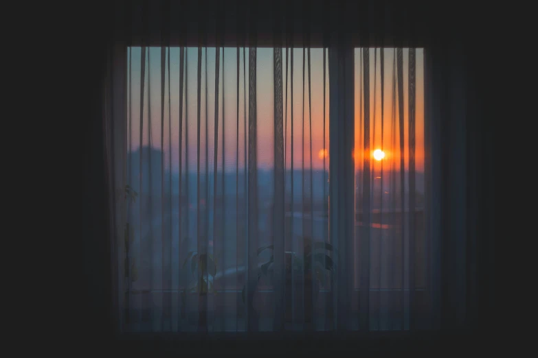 a sunset seen through the blinds on an open window