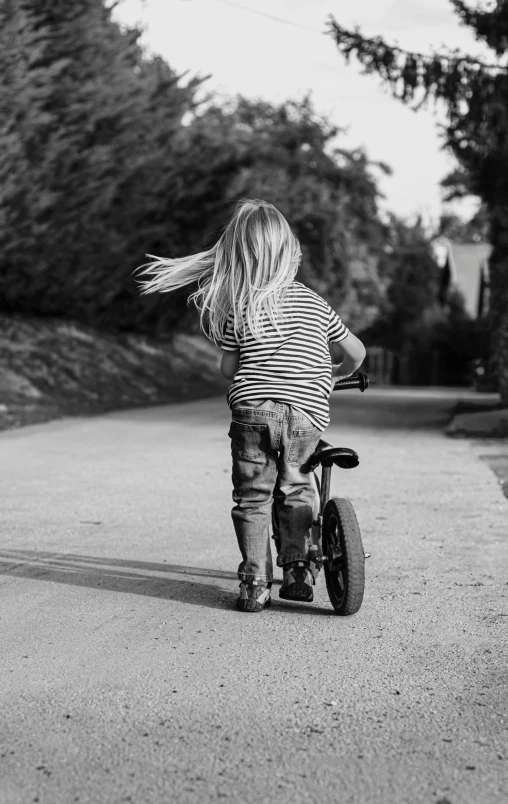 a small  rides a tiny bike down the street