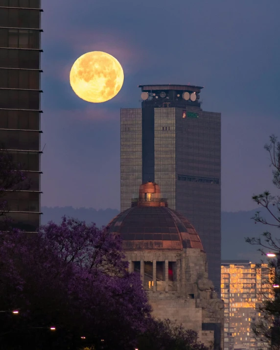 the full moon is rising over skyscrs in the city