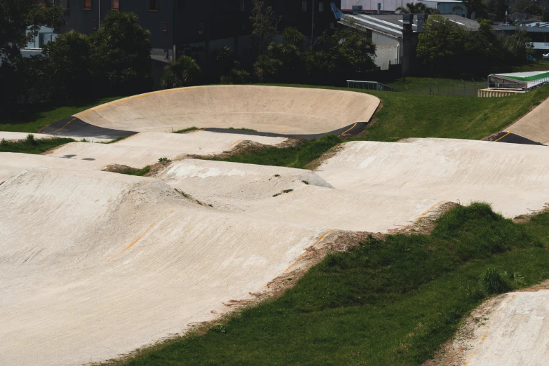 the skateboard park has ramps and grass growing around