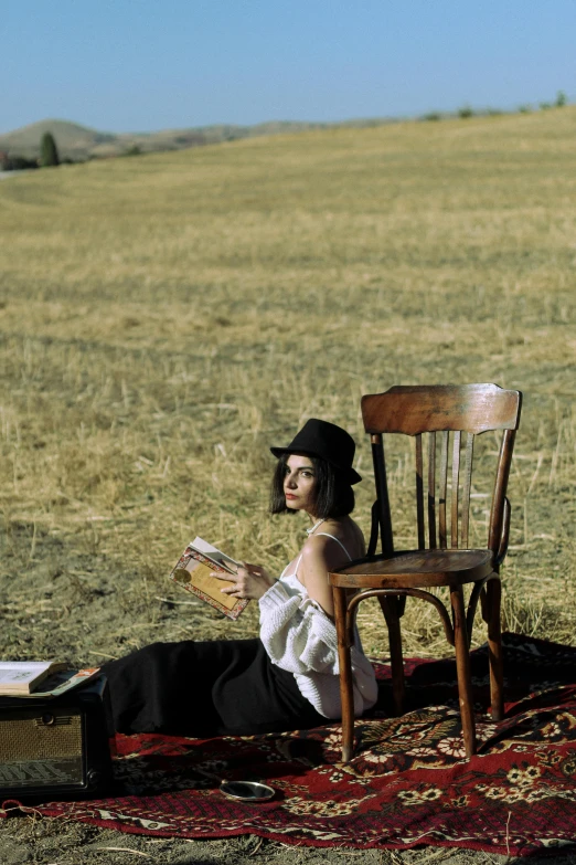 a woman sitting on top of a rug next to a chair