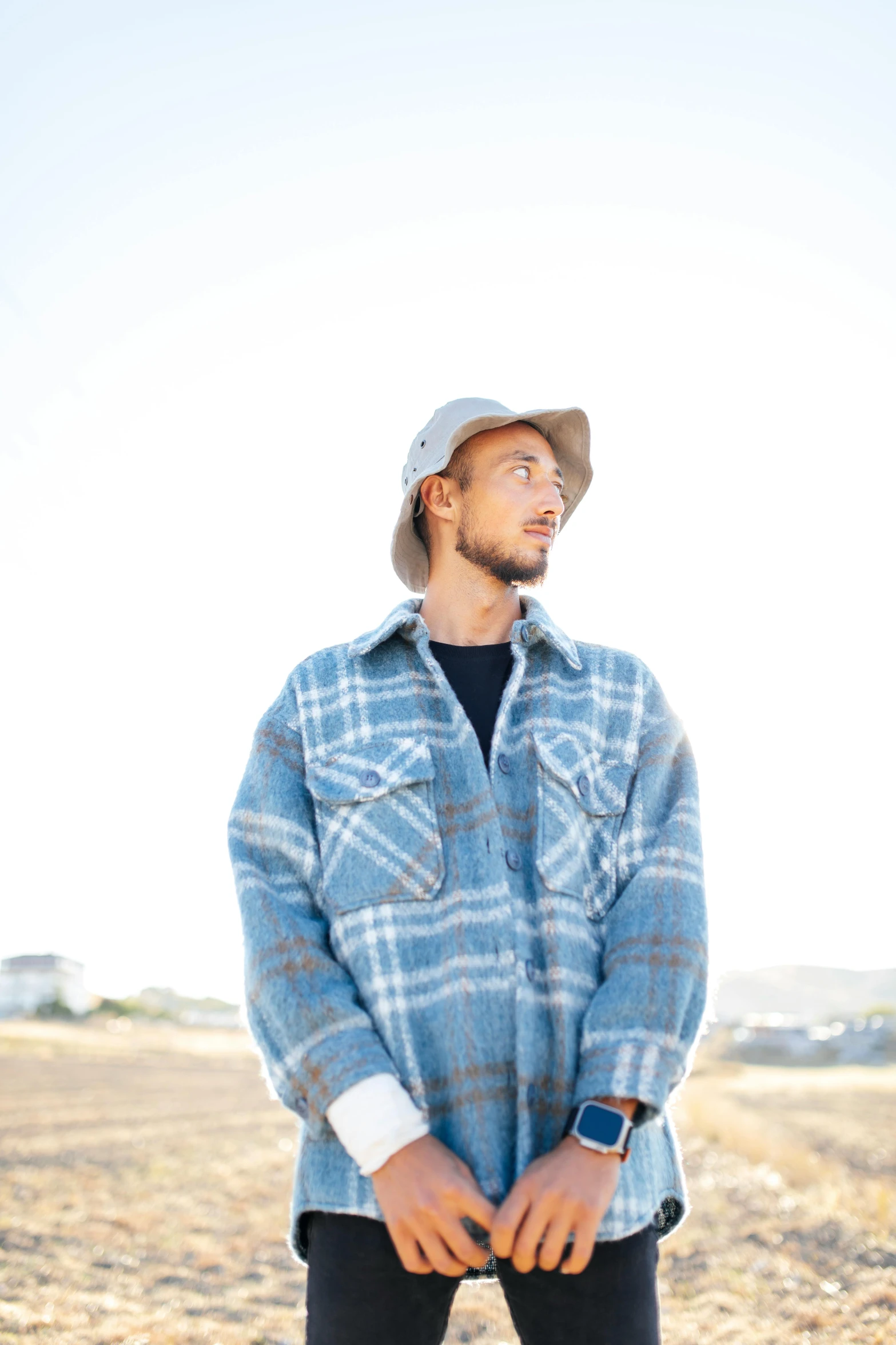 a man standing in a field wearing a hat and shirt