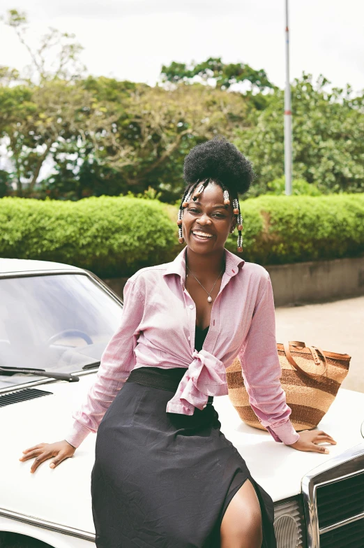 a woman in a black and white dress sits on the hood of a car