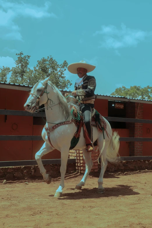 a cowboy riding his white horse in an arena