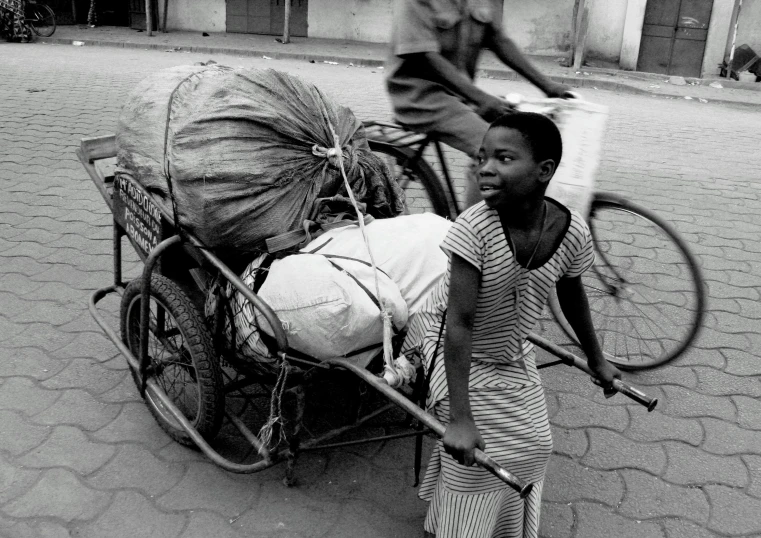 a black and white po shows a boy hing a cart with soing on it