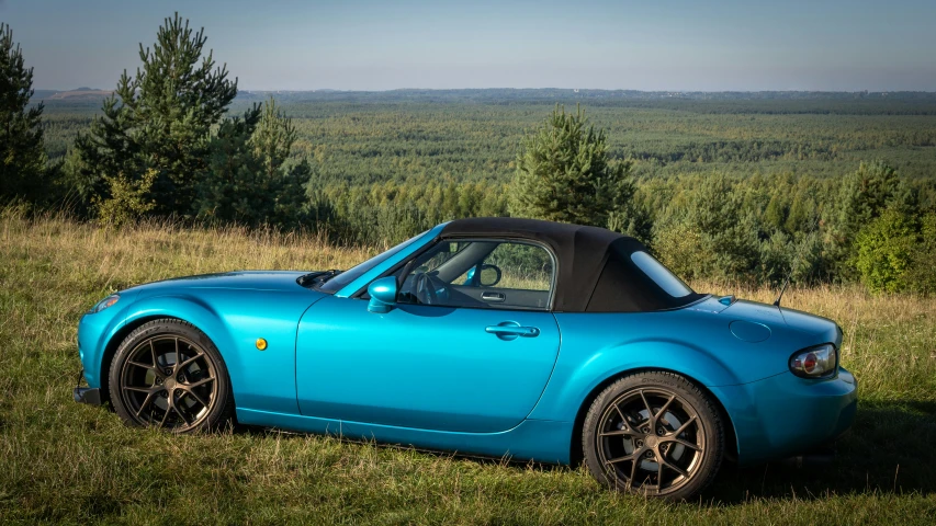 a bright blue convertible car parked on the side of a hill