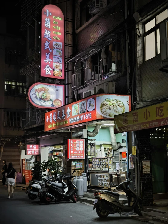 a street scene at night with signs and motorcycles