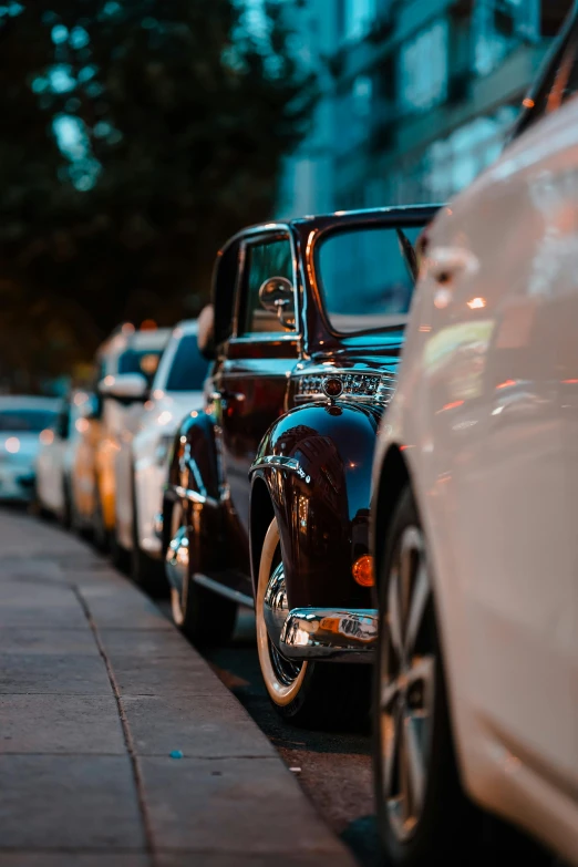 the row of classic cars are parked on the sidewalk