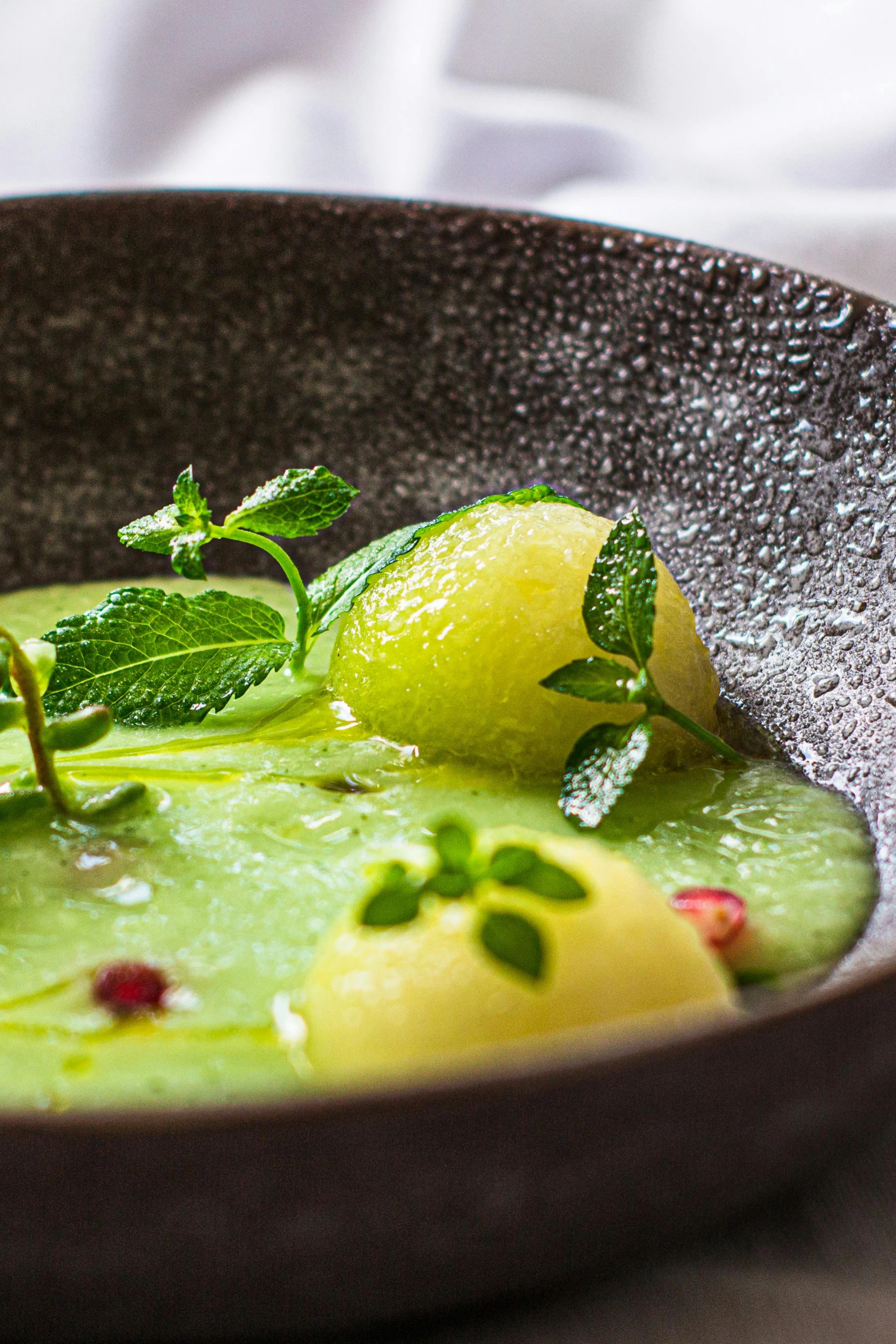 a bowl of soup with lemon and mint on it