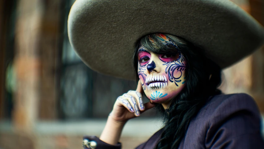 woman wearing a big hat and painted skull makeup