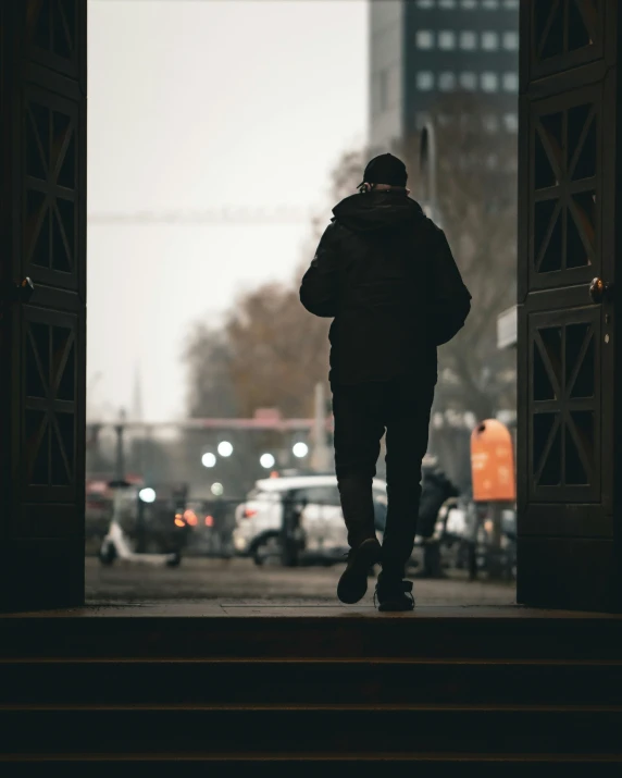 a man walking away from the camera into an open doorway