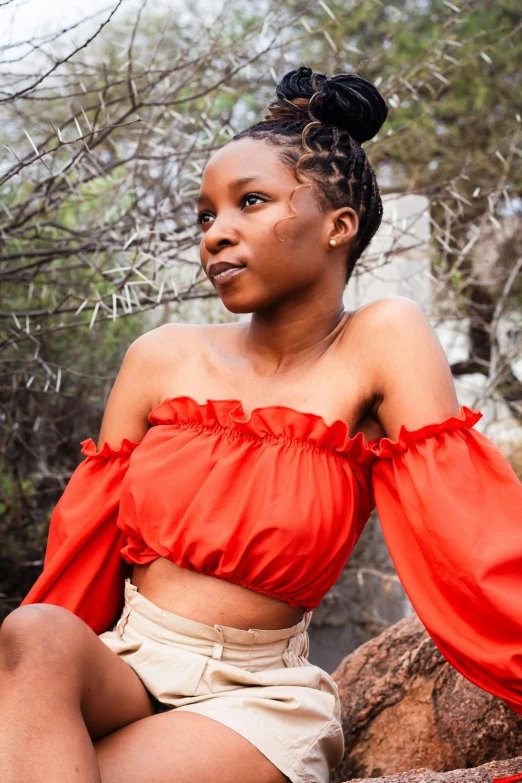 a woman with ids sitting on a rock wearing a red top