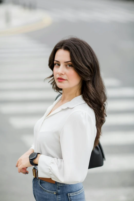 a woman standing in front of an intersection wearing jeans