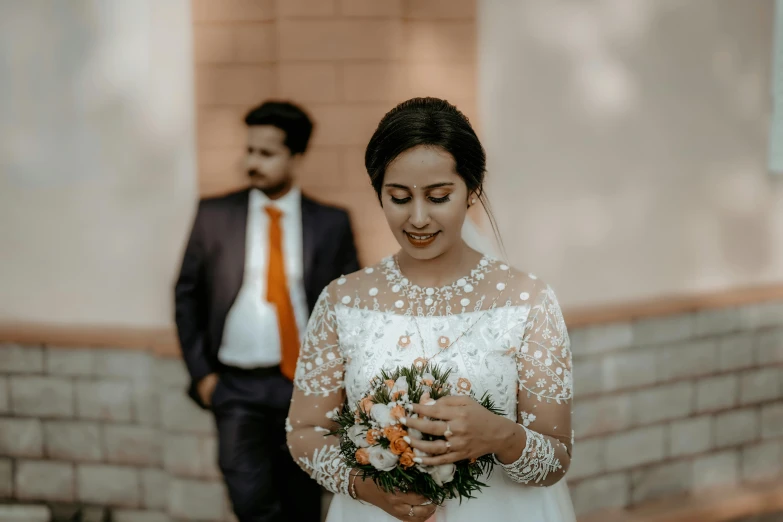 a bride and groom standing outside in front of a wall