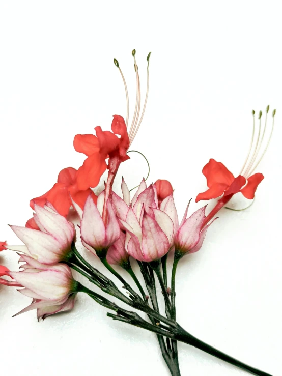 an artificial bouquet of red flowers on a white surface