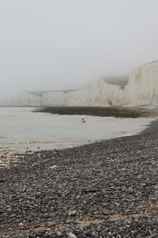 a beach that has a body of water next to the rocky shore