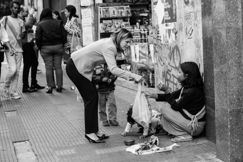 a black and white po of a woman handing soing out to someone