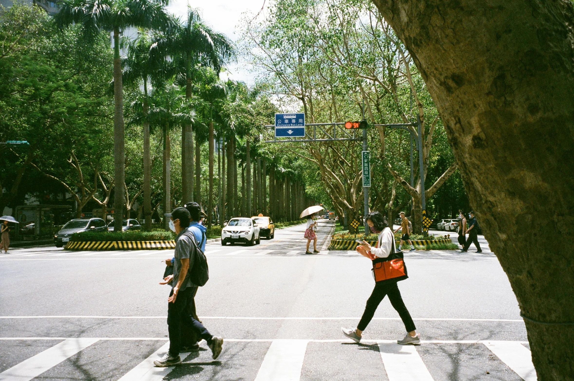 three men crossing the street, with a traffic light above them