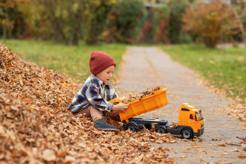 a child playing with a truck in the leaves