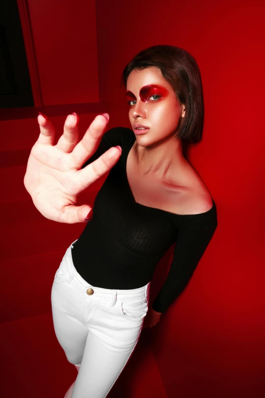 a woman is posing against a red background with her hand outstretched