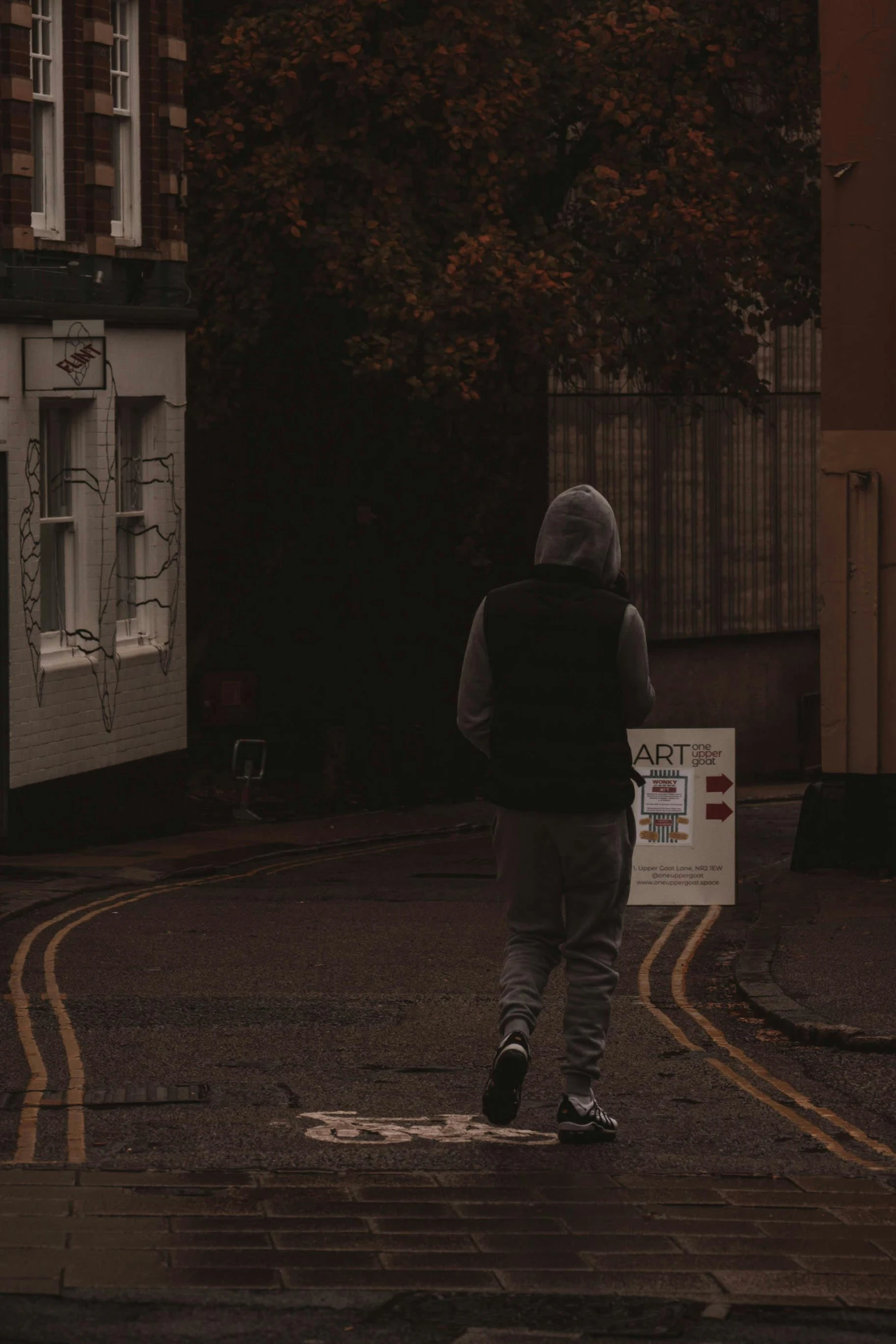 a person walking down a street next to a sign