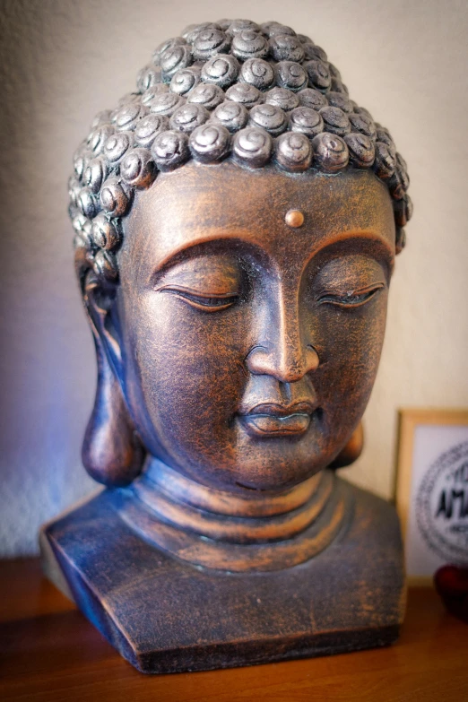 a metal buddha head is placed on top of a table