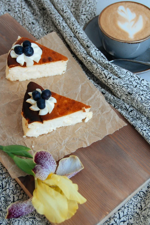 two pieces of pastry on a piece of paper with a cup of coffee in the background